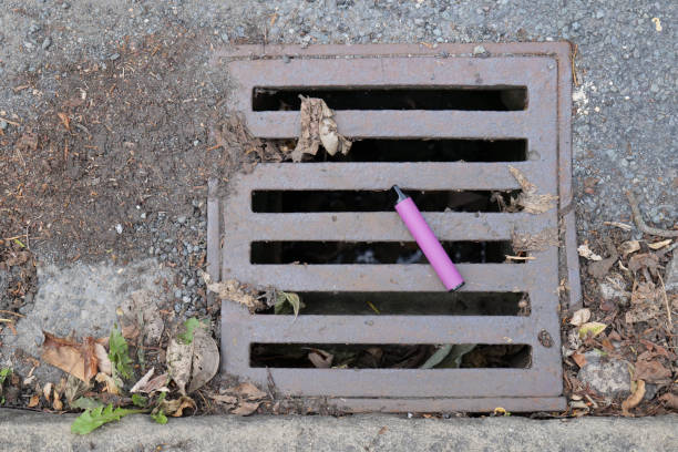 electronic cigarette vape left lying on drain cover - disposable imagens e fotografias de stock