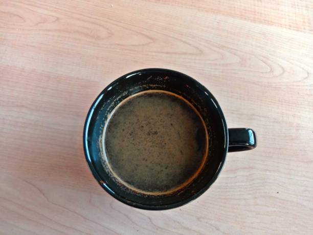 istock a black cup of coffee against a brown table color background 1569584465