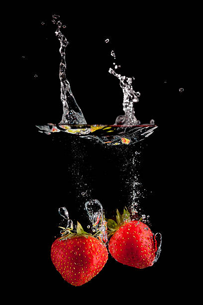 istock Two strawberries splashing on black background 156958894