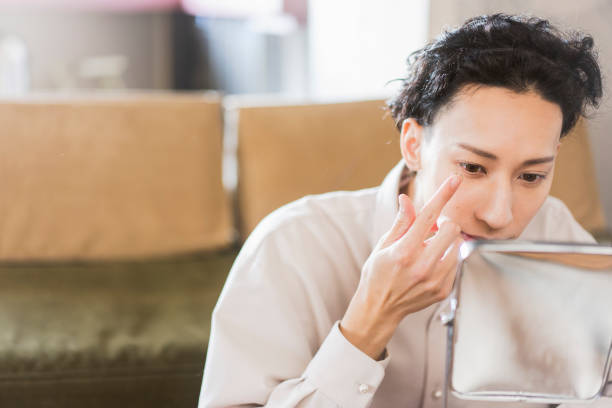 Life scene of a young Japanese man, put on contacts. Japanese man in his twenties living alone wearing contacts in the living room in the morning contact lenses man stock pictures, royalty-free photos & images