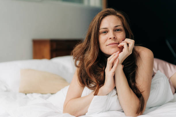 istock A young beautiful long-haired woman, lying in bed, boredly leaned her head on her hands. 1569607257