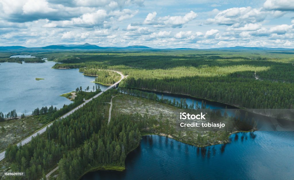 Roadtrip through Swedish summer landscape A country road through green forest and a wide river. Seen from above at summer in the landscape of Dalarna, Sweden. Varmland Stock Photo