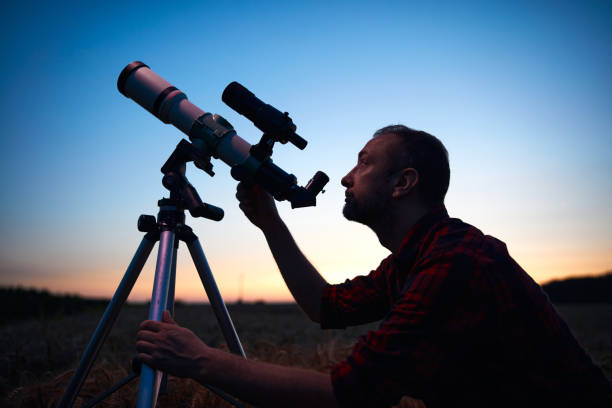 istock Astronomer looking at night sky with a telescope. 1569615826