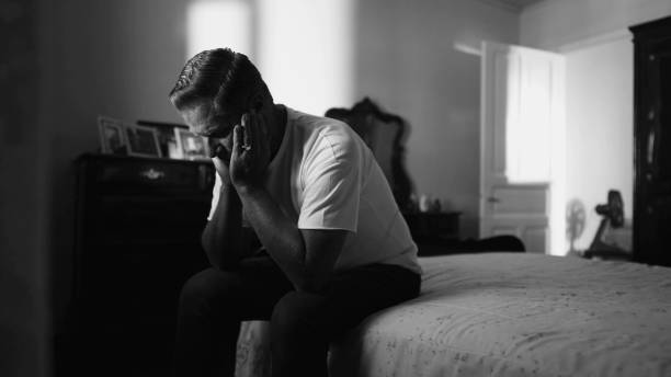 istock Older man suffering in quiet despair struggling with mental problems in home bedroom in monochrome black and white 1569627797