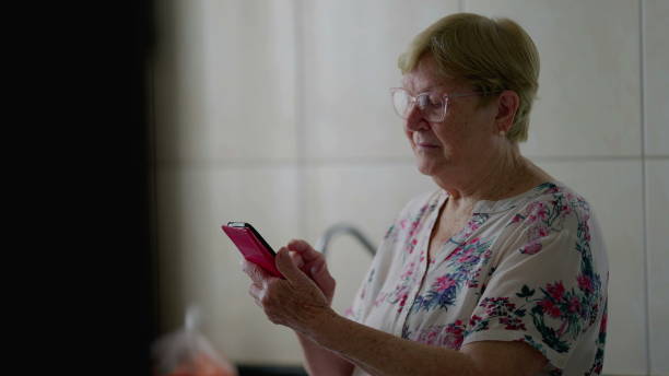 istock Elderly Woman Browsing Internet on Cellphone, Tech-Savvy Senior Engaged with Modern Technology at Home 1569635394