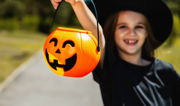 istock Happy Halloween! Cute little witch with a pumpkin. Soft focus 1569662128