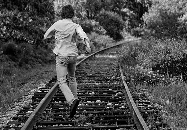 Young man of Indian ethnicity in emotional stress. He is sitting on railroad track.