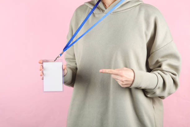 istock Young woman with Identification white blank id card on pink background 1569664277