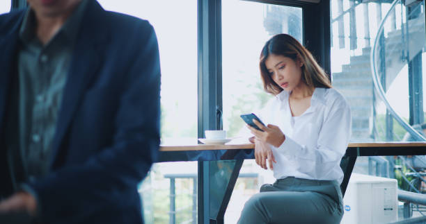 istock Young Asian businesswoman using smartphone at table in cafe 1569665370