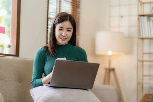 istock Happy asian girl holding tablet computer device using digital tablet technology sitting on sofa at home using app online shopping Read news, surf the internet, find a job. 1569691714