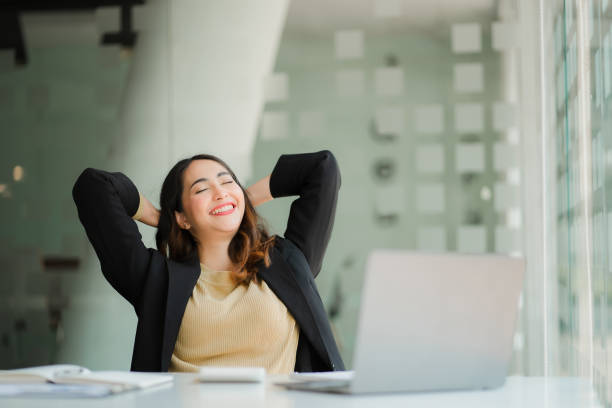 istock Asian woman stretches her arms behind her back to relax While working, sit at the table. office syndrome financial accounting business concept in the office 1569693387