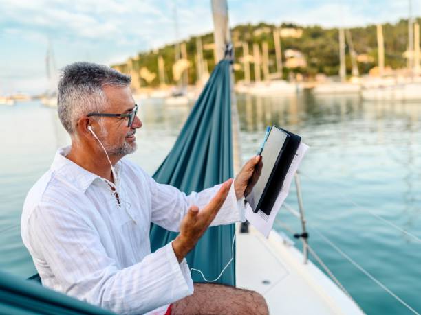 istock Businessman working while sitting on a hammock on a sailboat 1569701494