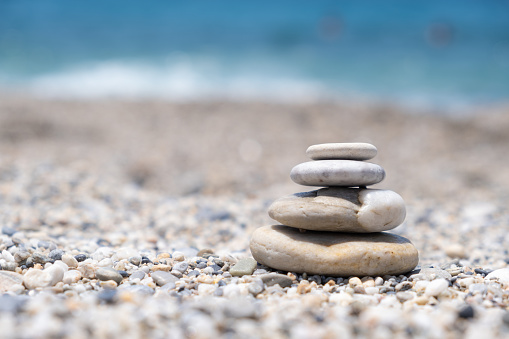 Round stones lie on top of each other in a column on the seashore on a sunny summer day. The concept of order and tranquility