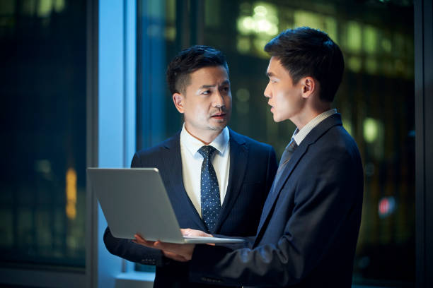 istock two asian businessmen discussing business in office using laptop computer 1569738310