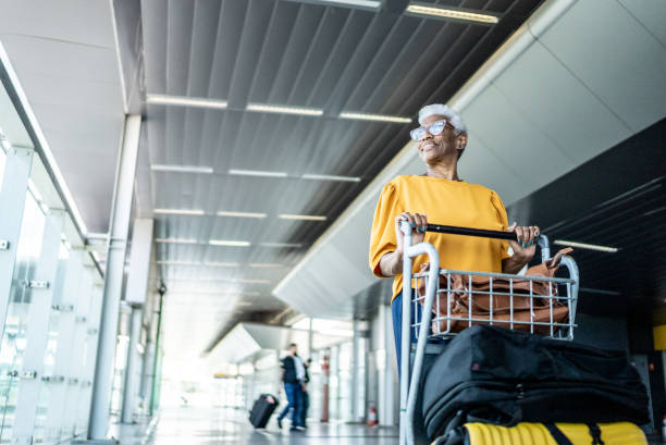 Senior woman walking with a luggage cart at the airport