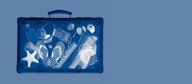 X-ray scan of a suitcase with travel accessories inside, summer vacations concept, copy space