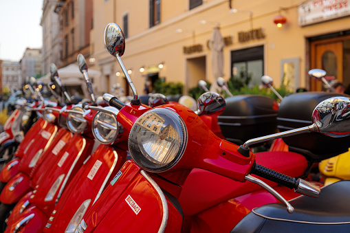 Rome, Italy - June 17, 2023: Group of red colored Vespa scooters parked. Scooter rental in town.