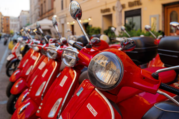 Rome, Italy - June 17, 2023: Group of red colored Vespa scooters parked. Scooter rental in town.