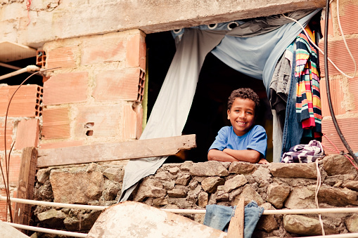 A young Brazilian boy from a Rio de Janeiro favela smiles from his home window.
