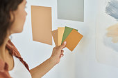 Hand of young woman with palette of color swatches choosing one for wall