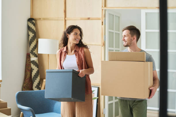 istock Happy young husband and wife looking at each other while carrying boxes 1569782095