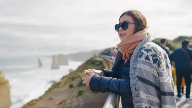 Young female traveler look out to the ocean at The Twelve Apostles, Victoria Australia