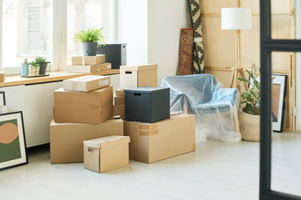 istock Stacks of packed cardboard boxes standing on the floor by windowsill 1569791923