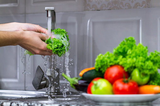 Woman washing vegetables for cooking salad in the kitchen. Right and healthy food, proper nutrition