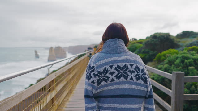 Young female traveler look out to the ocean at The Twelve Apostles, Victoria Australia