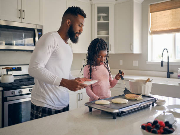 istock Father and Daughter Cooking and Eating a Pancake Breakfast 1569803399
