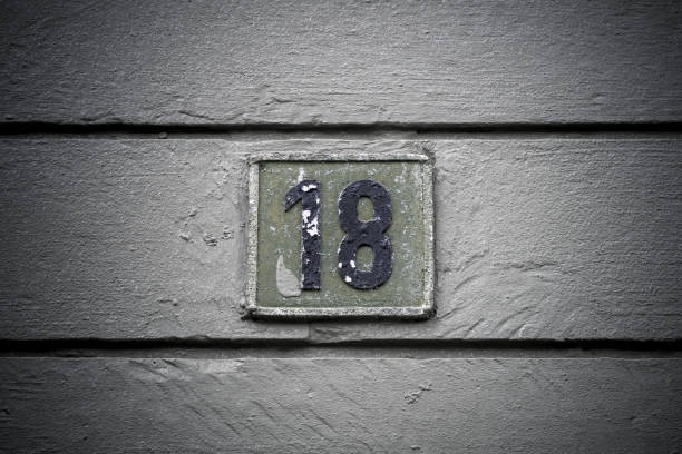 istock Number eighteen weathered sign on plank background 1569806622