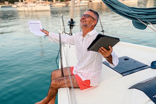 Businessman working while sitting on the deck of a sailboat