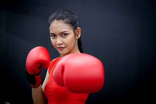 Determination of young asian woman having motivation boxing in fitness gym, active sport and workout, training boxing with strength and confidence, health and wellness, exercise and punch with cardio.