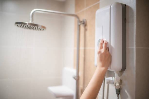 Woman hand adjust temperature at electric water boile. Woman hand adjust temperature at electric water boiler with shower and rain water blur background and space, woman using water boiler in bathroom at home. woman hot shower stock pictures, royalty-free photos & images