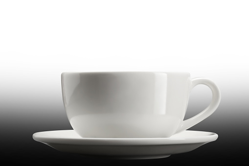 Dishware or crockery background. Close-up of empty white coffee cup on dish isolated on a white background. Macro.