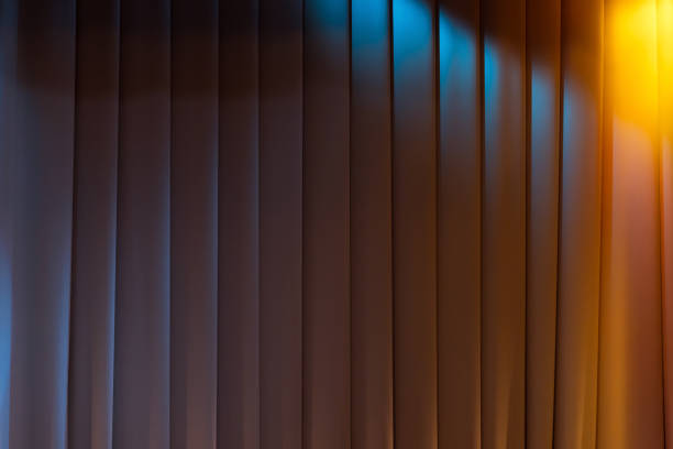 istock Closed white wavy theatrical curtain with stage illumination 1569835890