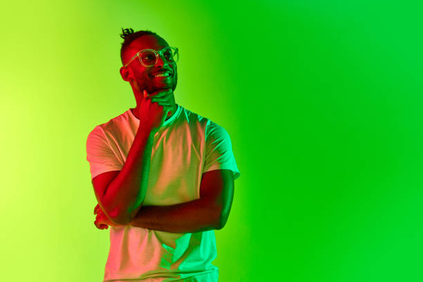 istock Thoughtful young man with dreadlocks, guy thinking over gradient yellow-green background in neon. 1569844319