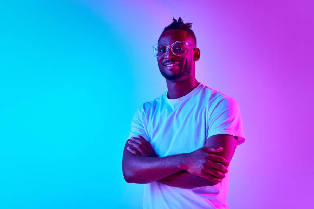 istock Full length african man smiling and looking at camera crosed hands over colorful studio background in neon. 1569844387