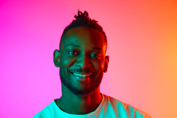 istock Portrait with smiling african man looking at camera over gradient colorful background in neon. 1569844933