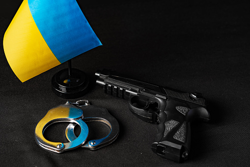 Ukrainian flag and handcuffs on black background close up, concept of crime and justice in the country