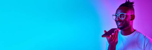 istock Banner with african man with dreadlocks looking away holding phone and calling over gradient blue-pink background in neon. 1569850494