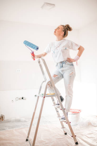 istock Woman standing on a ladder and thinking how to paint the ceiling 1569860833
