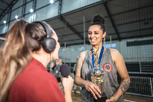 Mature female volleyball player being interviewed after win a match on the sports court