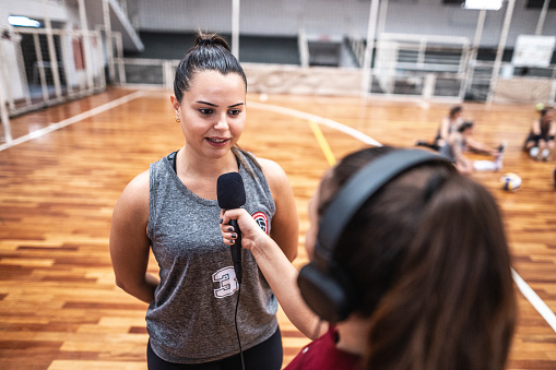 Young female volleyball player being interviewed on the sports court