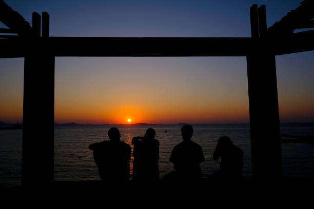 Friends enjoy the sunset on the seafront of Naxos, Greece on July 7, 2023.
