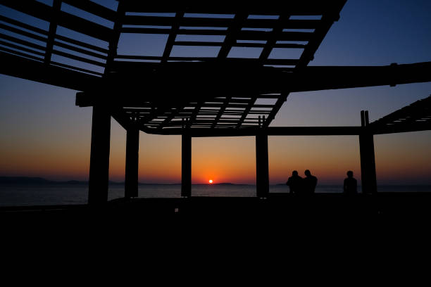 Friends enjoy the sunset on the seafront of Naxos, Greece on July 7, 2023.