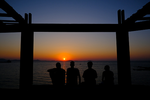 Friends enjoy the sunset on the seafront of Naxos, Greece on July 7, 2023.