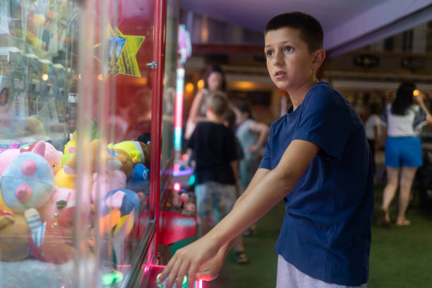 istock Young Boy Playing A Claw Crane Game 1569894506