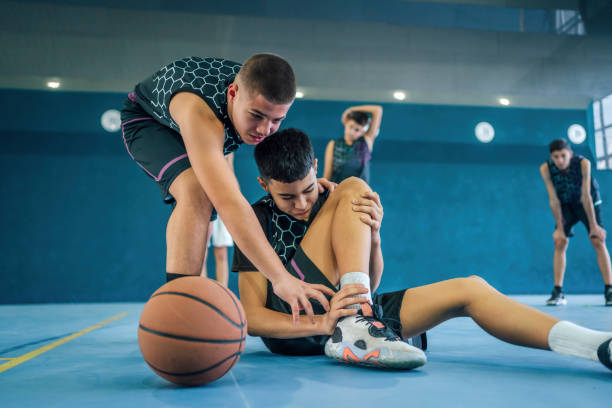 un joueur de basket-ball adolescent se blesse dans le match - child basketball uniform sports uniform photos et images de collection