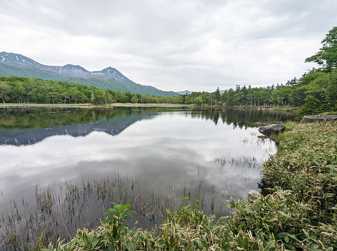 Lake Niko, or Second Lake, reflects the Shiretoko Mountains and the increasing clouds over Shiretoko Peninsula. Spring afternoon in eastern Hokkaido Prefecture.